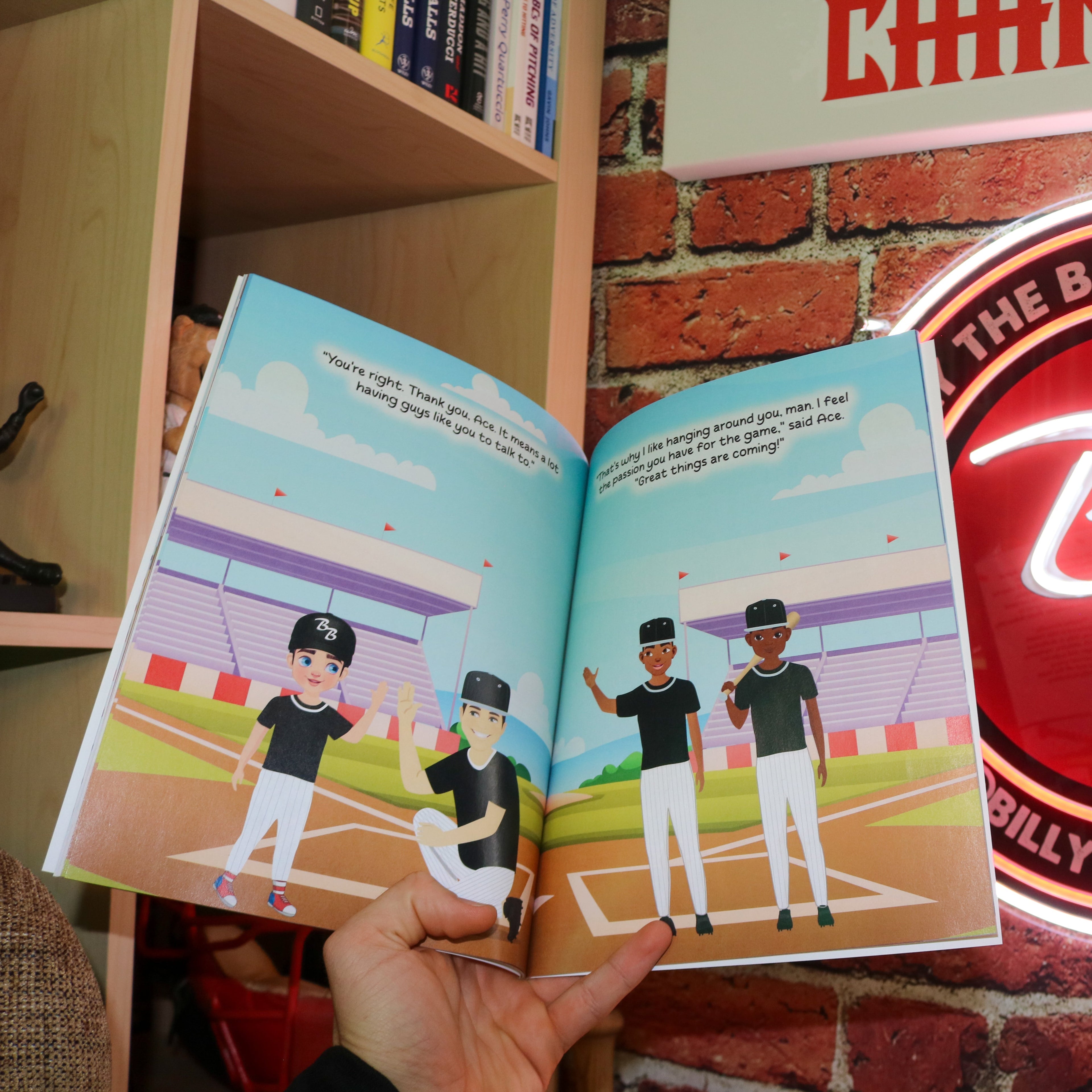 Open book with baseball-themed illustrations next to a neon sign on a brick wall.